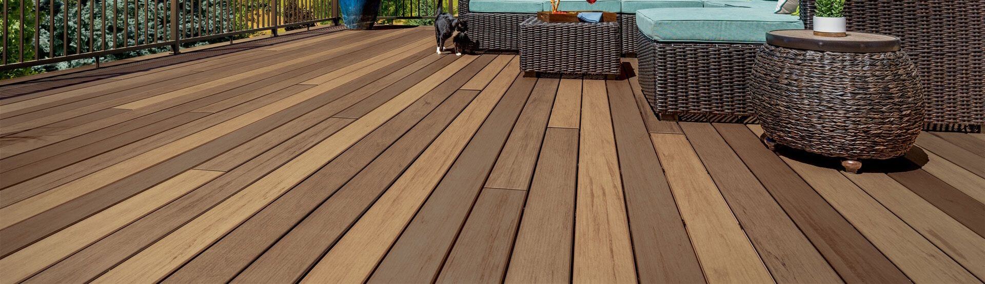 Composite deck featuring multi-tonal wood grain boards and outdoor wicker furniture by Xtreme Exteriors