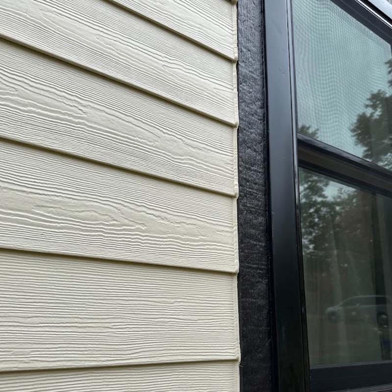 Cream colored board and batten siding with black window and black window trim close up