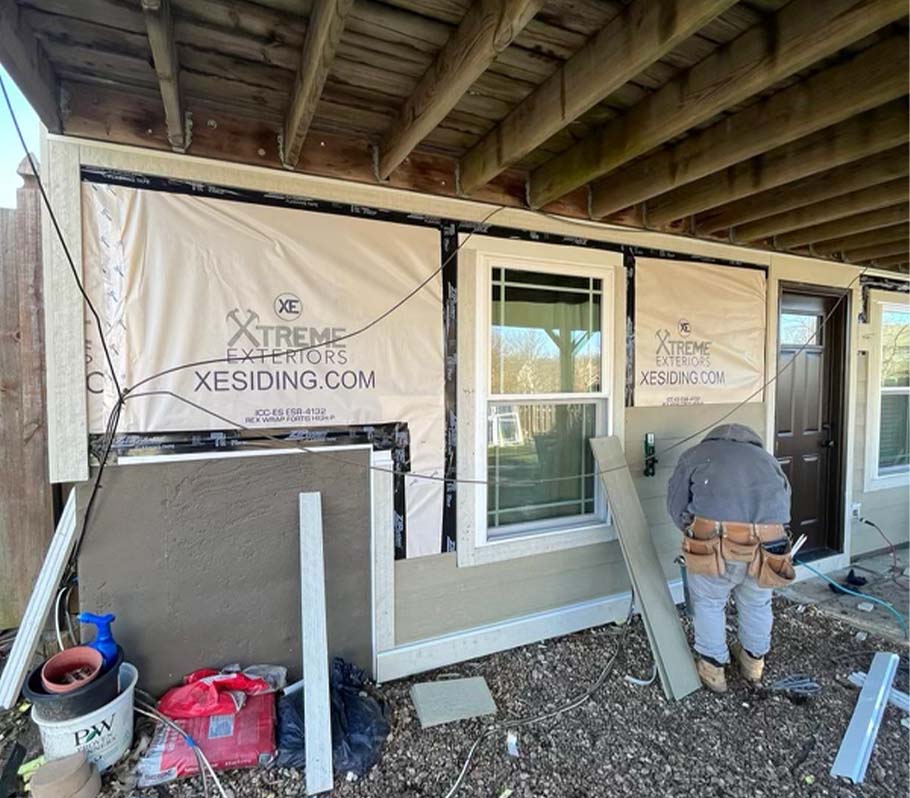 Xtreme Exteriors siding contractor on the job installing new siding under a deck