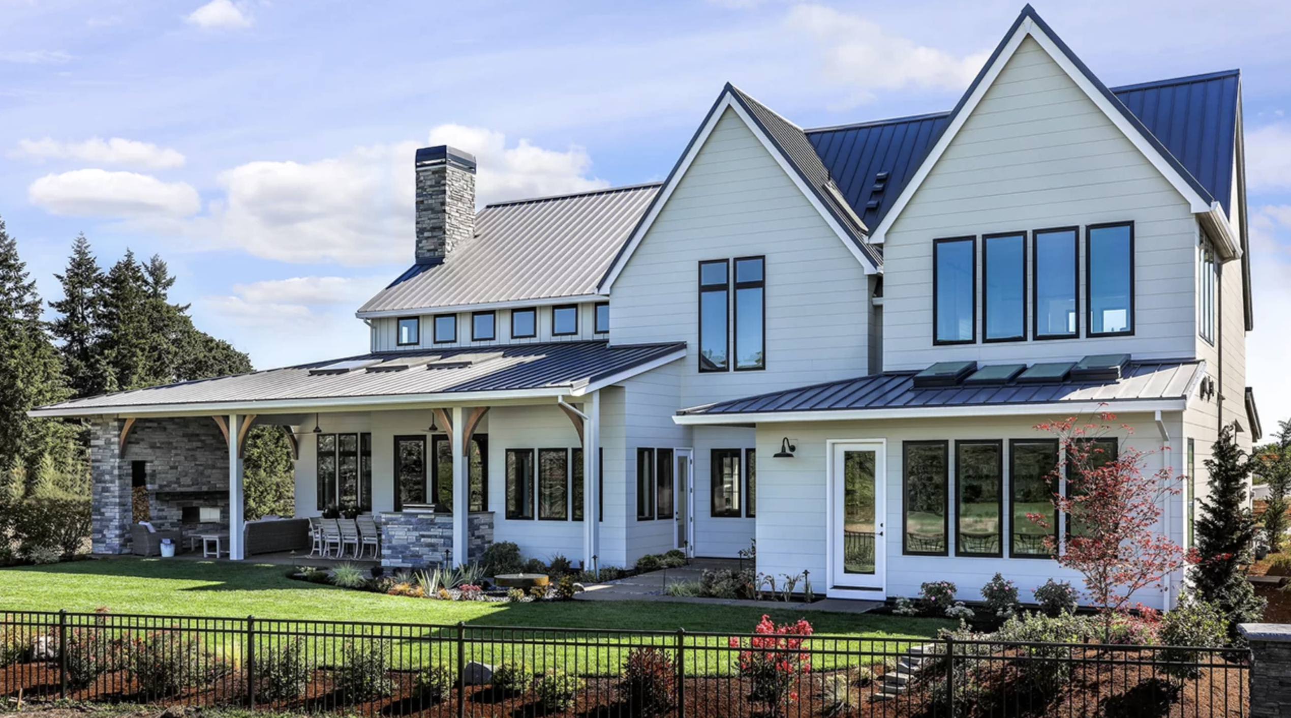 sisometric view of a large multistory residential home with white siding and black windows with skylights