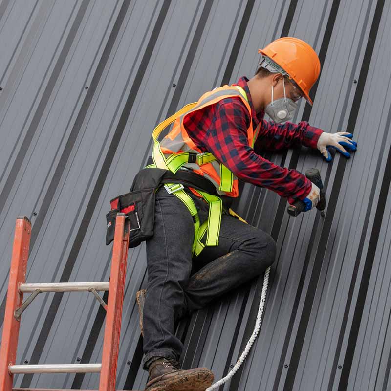 Commercial roofing contractor with tools and hardhat on a roofing maintenance project