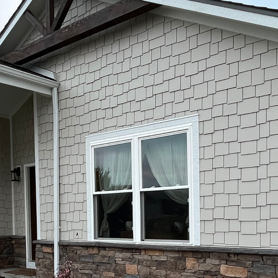 Cream shake siding on a house with stone veneer with realistic wood beam truss