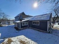 a home with blue siding surrounded by snow