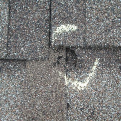 a spot of hail damage circled in chalk on a roof