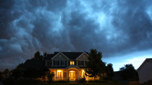 Dark clouds in the evening above a home with lights on at Xtreme Exteriors in Rogers, AR