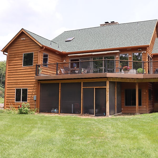 A house with a newly installed deck, black roof and orange siding made by an exterior contractor in Rogers