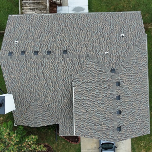 Aerial view of a house with a black roof installed by a roof replacement service contractor