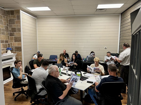 Group of people around a table in a meeting room with papers.