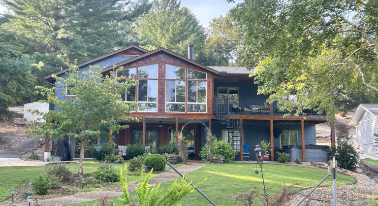 A two-story house with large windows and a balcony, surrounded by greenery and a well-kept lawn Xtreme Exteriors in Rogers, AR | Xtreme Exteriors