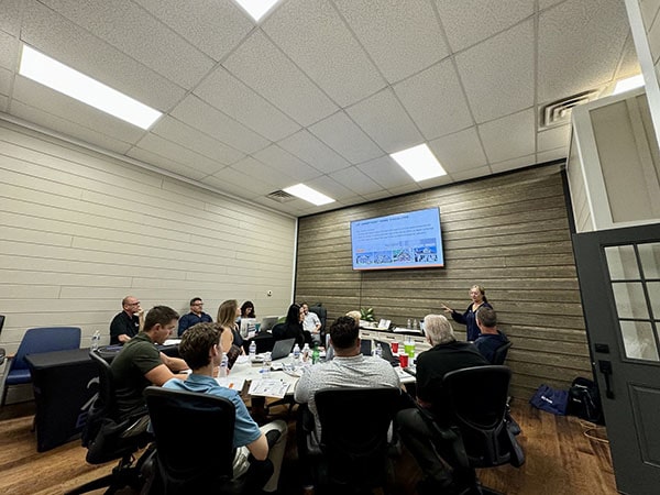 Group of professionals in a meeting room with a presentation on screen.