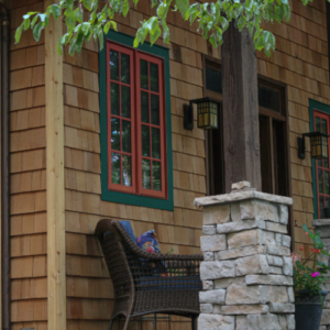 Brown Cedar Siding with green and yellow window and a black chair