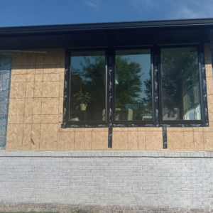 black-framed window with three sections is being installed in a home by Xtreme Exteriors window installation services