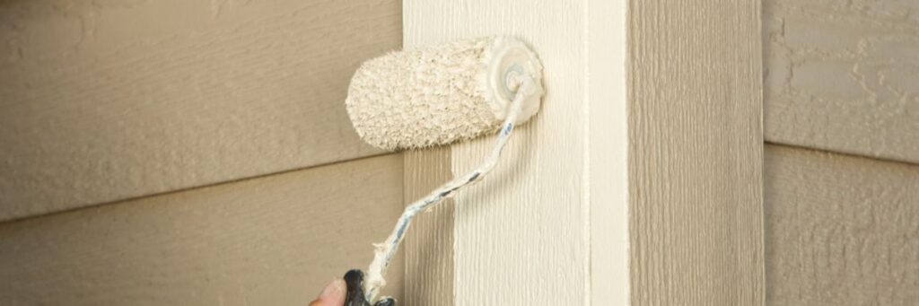 A. exterior painters' paint roller with a thick nap applying beige paint to a textured wall