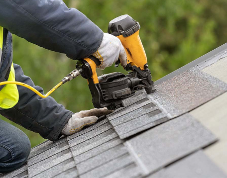 Contractor installing asphalt shingles with a pneumatic nail gun for roof replacement by Xtreme Exteriors