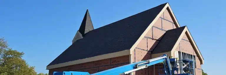 Ongoing church roof replacement with new shingles and blue construction lift by Xtreme Exteriors in Nixa, MO