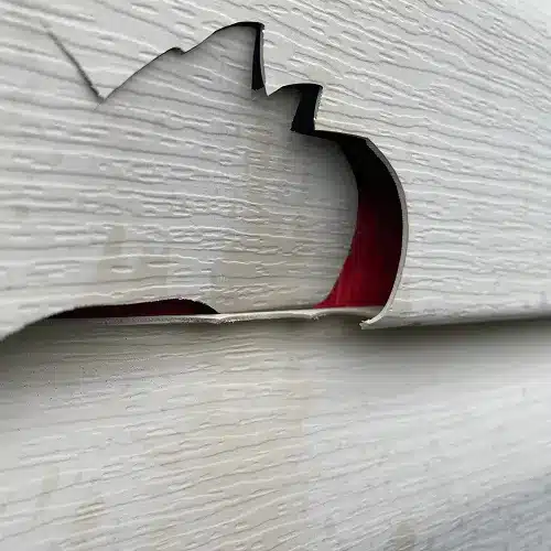 Close-up of cracked siding panel requiring emergency repair services in Sikeston by Xtreme Exteriors