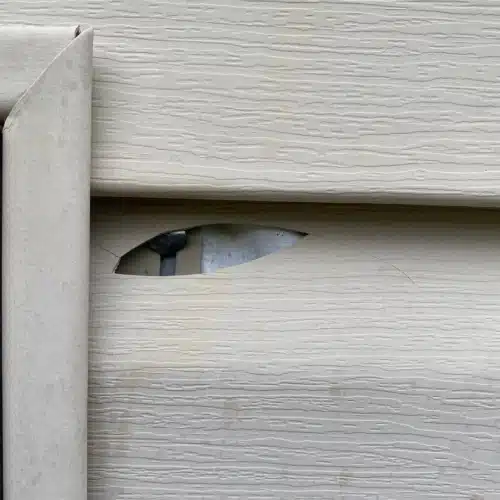 Close-up of siding crack from storm damage, showing when Springdale homes require siding repair