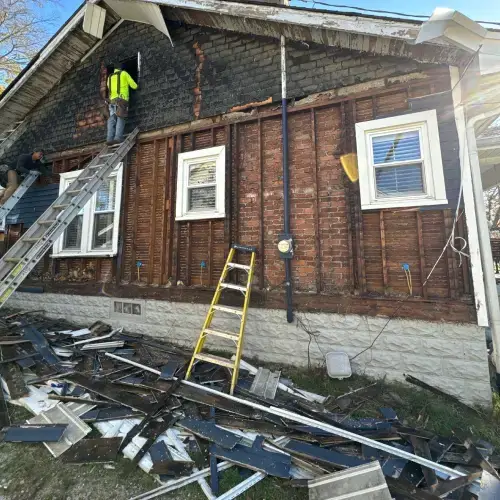 Crew performing siding maintenance on a home exterior in Pittsburg, with removed siding panels and visible structural repairs