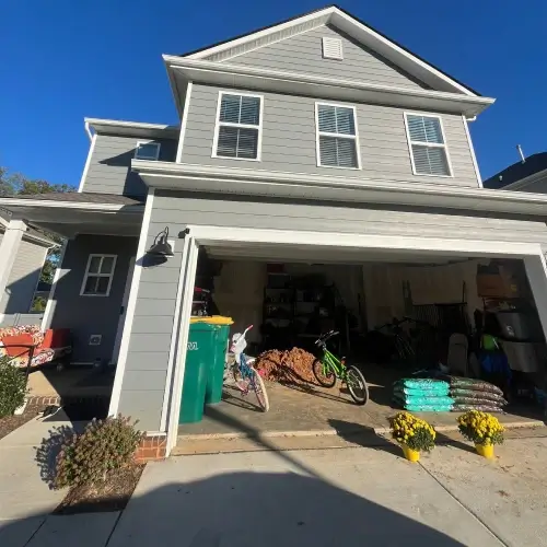 Choosing a siding contractor in Nixa, MO with new gray siding, clean garage entry, and landscaped driveway by Xtreme Exteriors