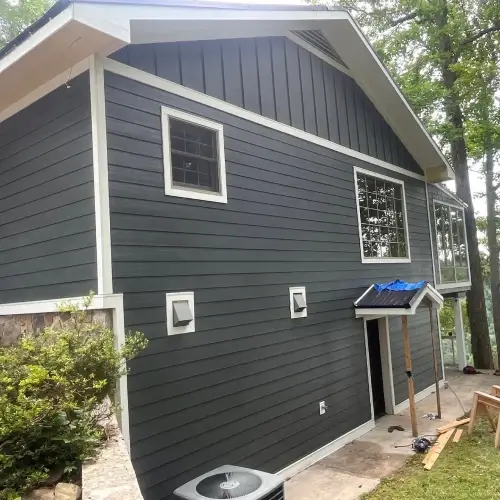 Modern home exterior in Nixa, MO featuring newly installed dark gray lap siding with white trim and accent vent details, completed by Xtreme Exteriors as a guide to siding options