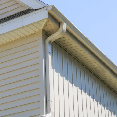 Corner of a home showing clean tan vertical and horizontal vinyl siding styles, soffit, fascia, and a downspout, illustrating the quality exterior work and diverse siding styles shawnee offered by Xtreme Exteriors in Nixa, MO