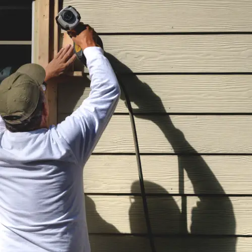 Professional installer working on home siding in Nixa, MO, showcasing Xtreme Exteriors’ siding warranty services