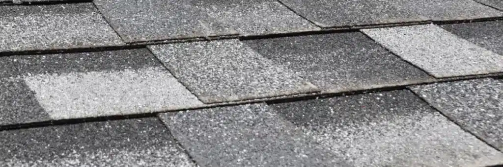 Extreme close-up of dark gray asphalt roofing shingles showing noticeable granular loss and weathering, which requires professional roofing storm damage repair by Xtreme Exteriors in Nixa, MO