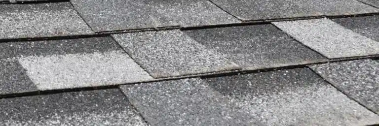 Extreme close-up of dark gray asphalt roofing shingles showing noticeable granular loss and weathering, which requires professional roofing storm damage repair by Xtreme Exteriors in Nixa, MO