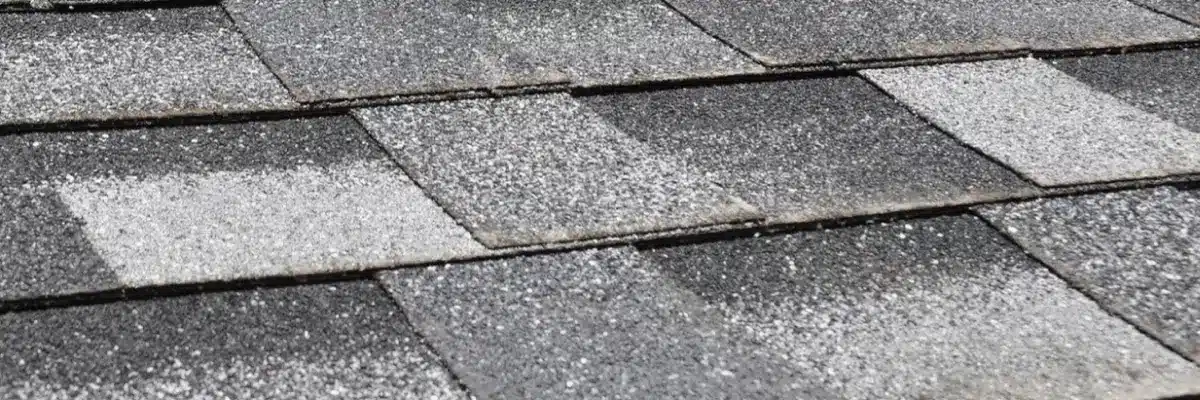 Extreme close-up of dark gray asphalt roofing shingles showing noticeable granular loss and weathering, which requires professional roofing storm damage repair by Xtreme Exteriors in Nixa, MO
