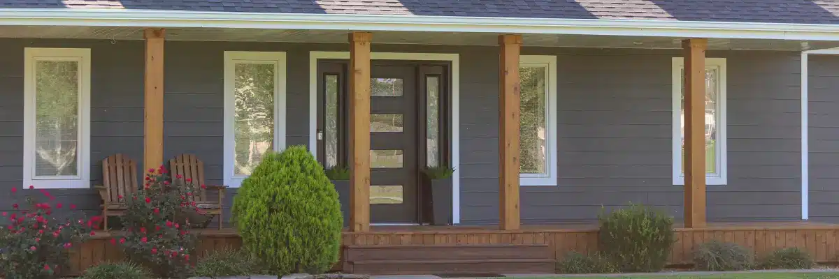 Close-up of a modern home exterior featuring dark gray horizontal siding style, white trim, wooden porch columns, and a contemporary front door, highlighting Xtreme Exteriors' work on siding styles shawnee from Nixa, MO.