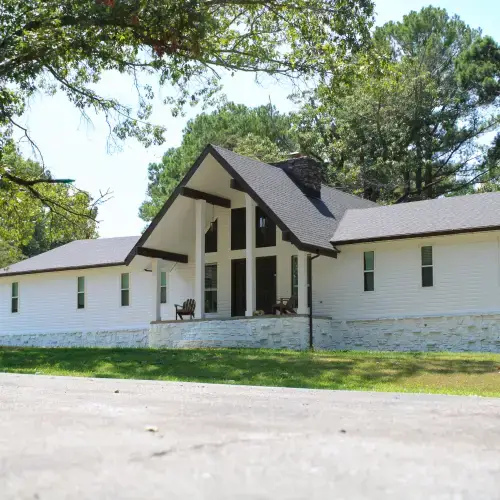 A striking white horizontal siding style home featuring a tall black-trimmed gable entrance and white stone skirting, showcasing popular siding styles shawnee installed by Xtreme Exteriors Nixa, MO.